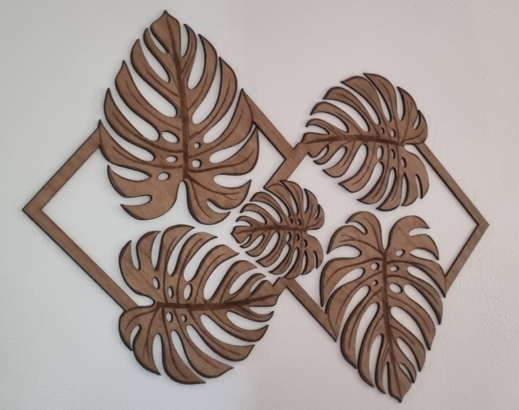 Décoration murale en bois composée de quatre feuilles de Monstera imbriquées dans des cadres en losange, réalisée en découpe et gravure laser.